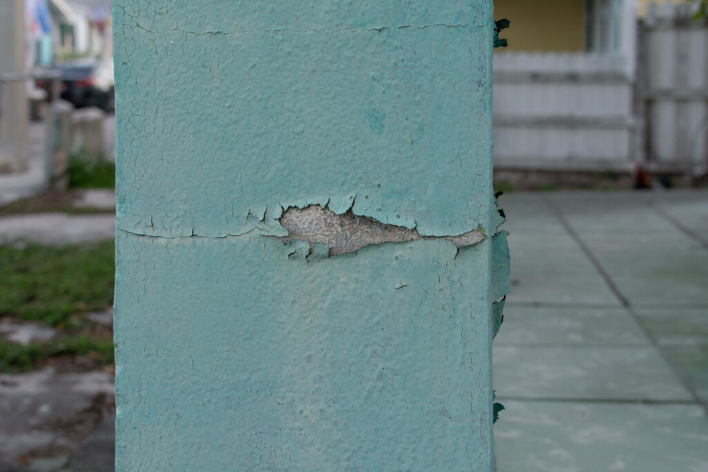 “Painted column with cracked and peeling paint revealing the underlying substrate.”