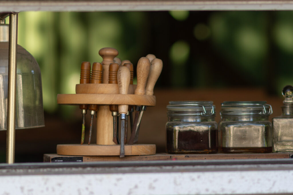 “Wood-handled tools arranged on a stand beside glass jars on a shelf.”